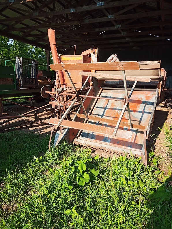 A large pull behind combine, it looks very mechanical and is a faded red.