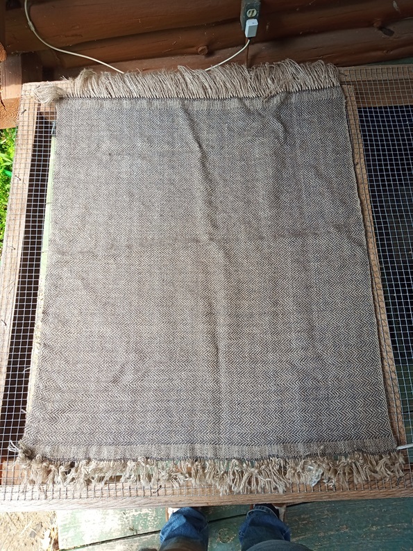 A grey and tan piece of fabric, around four feet by three feet with a herringbone pattern.