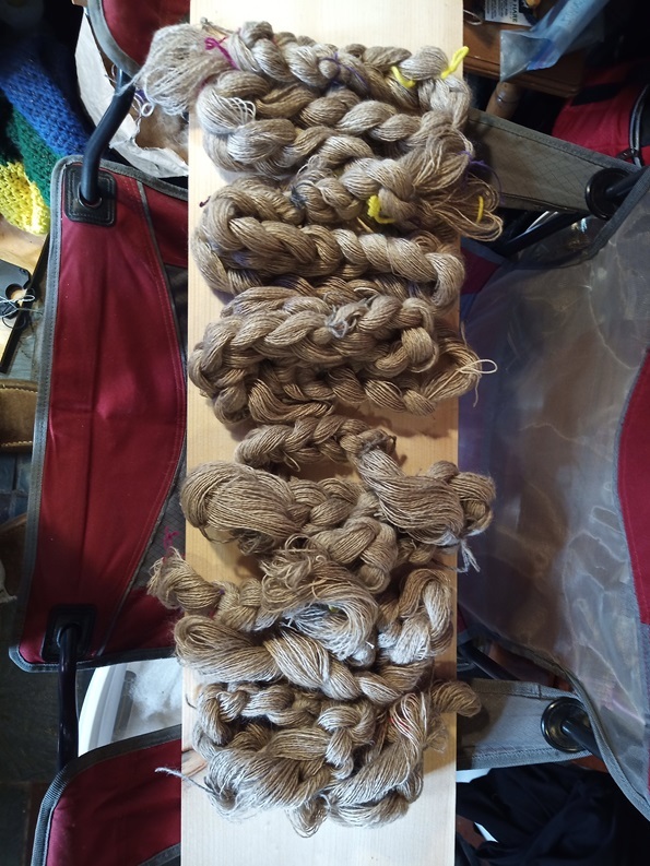 A bunch of warp chains laying on a board on top of a camping chair.