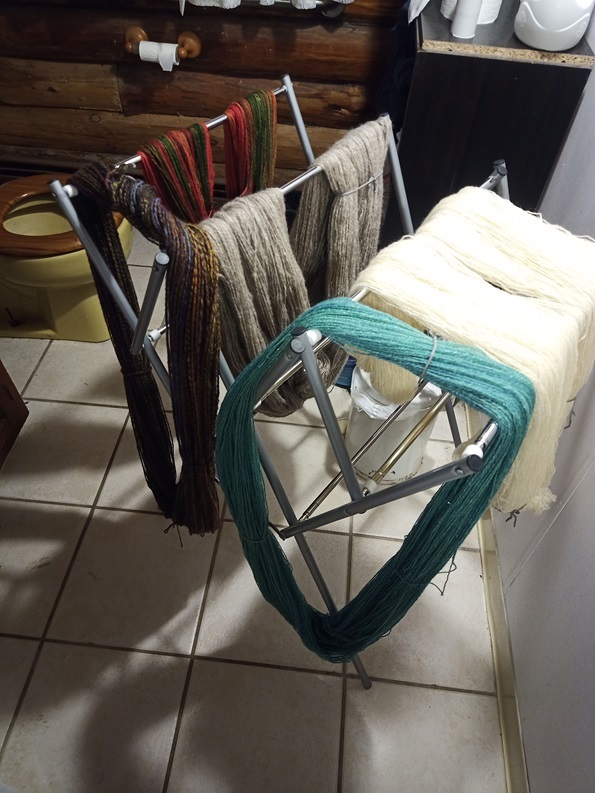 Five skeins of yarn in different colors are draped over the bars of clothes drying rack.