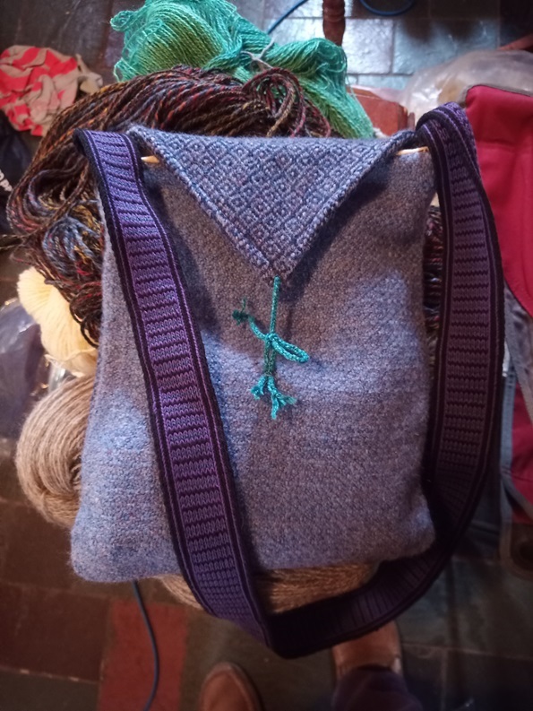 A diamond patterned bag with a zigzag striped strap.