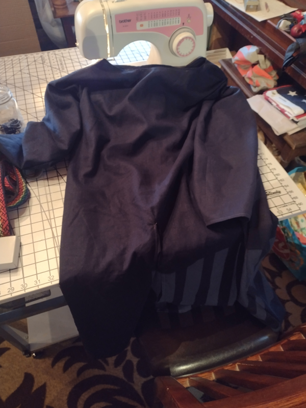 A deep blue tunic is laying in front of a sewing machine.
