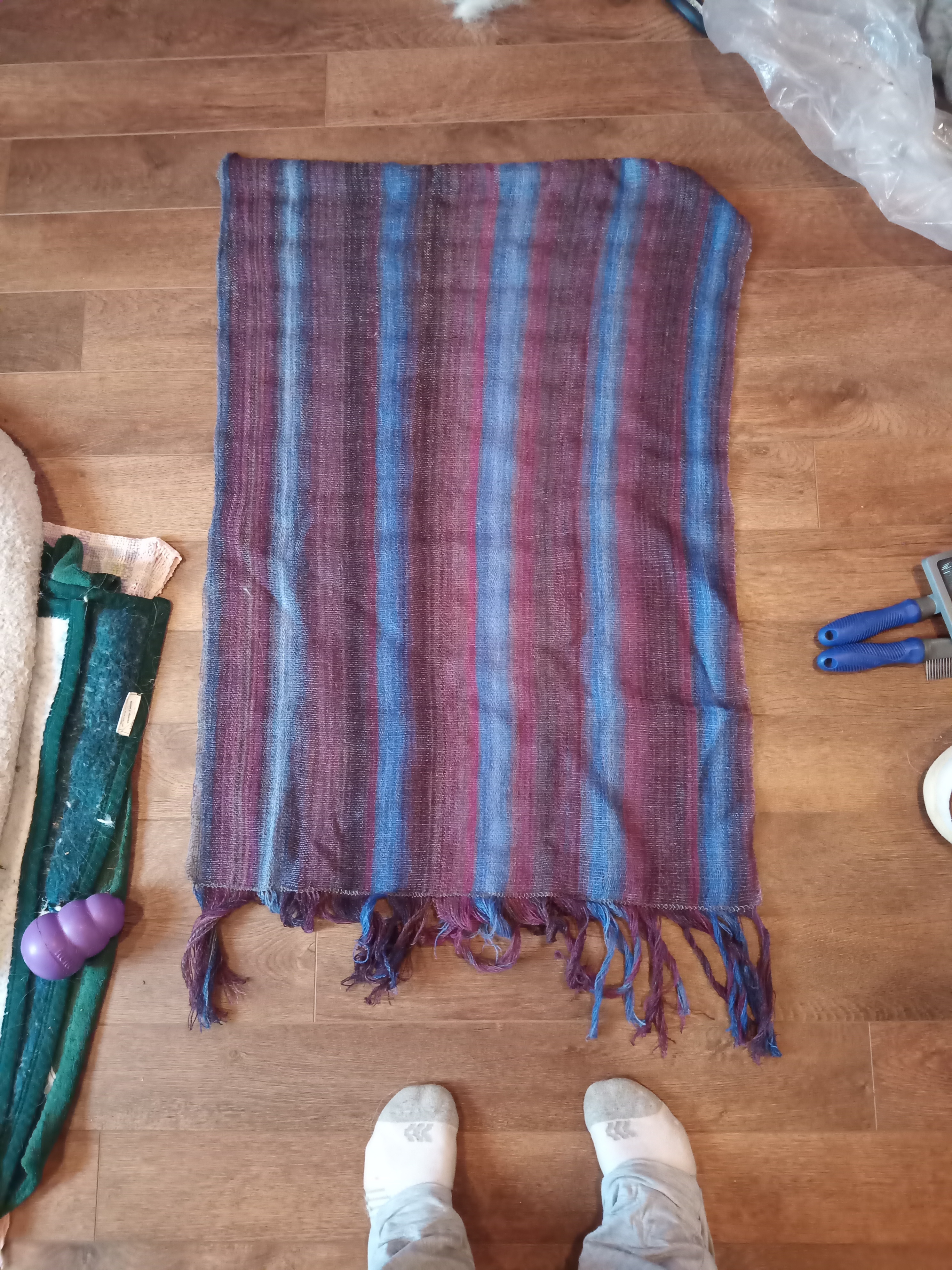 A variable blue, purple, brown piece of cloth lays on a wood floor.
