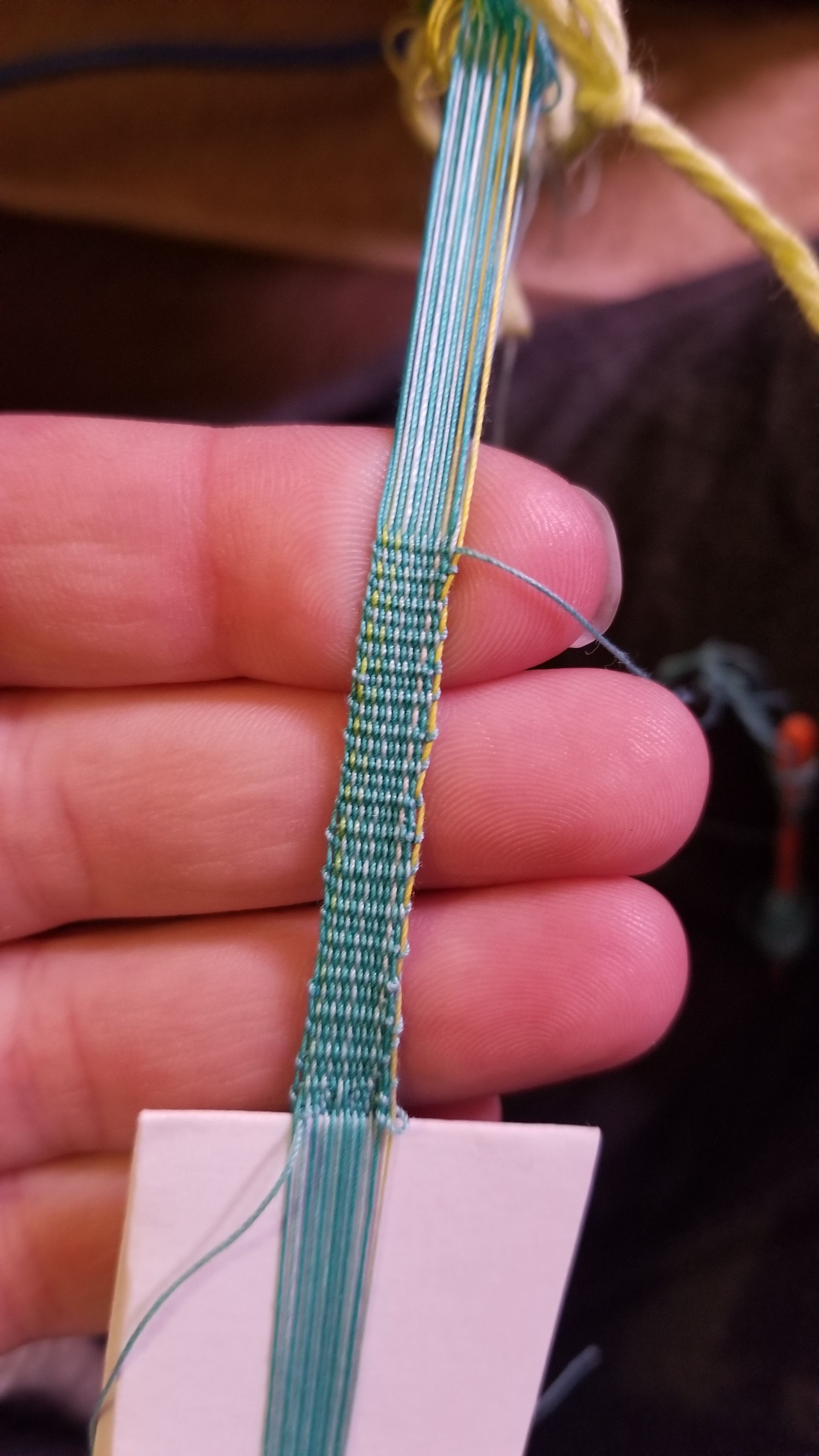 An incredibly tiny band of woven thread held in my hand.