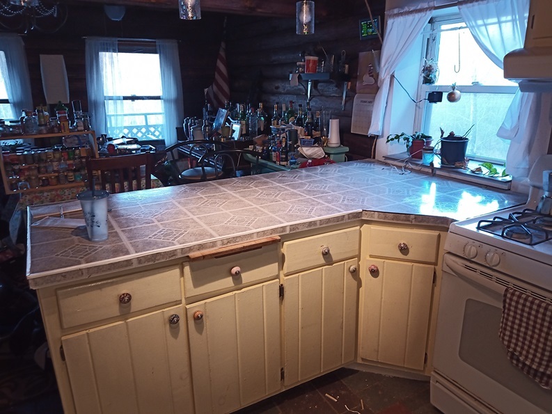 Ugly grey tile laminate on a large floating countertop. There's a lot of stuff in the background.